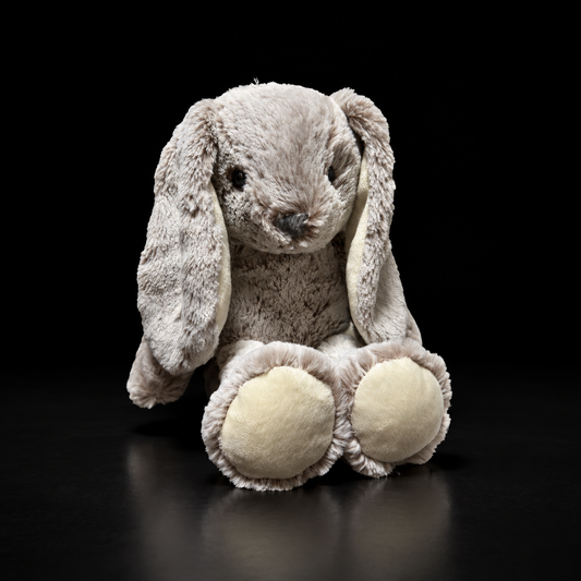 Conejo de peluche gris de orejas largas sobre fondo negro