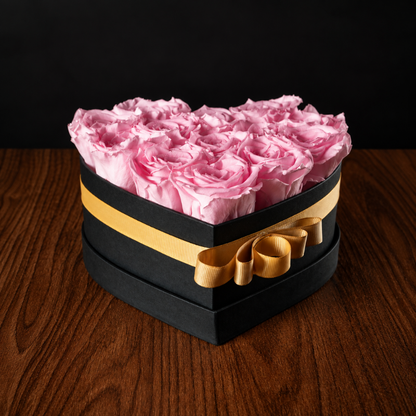 Caja en forma de corazón con rosas naturales preservadas en color rosa claro y lazo dorado para regalo