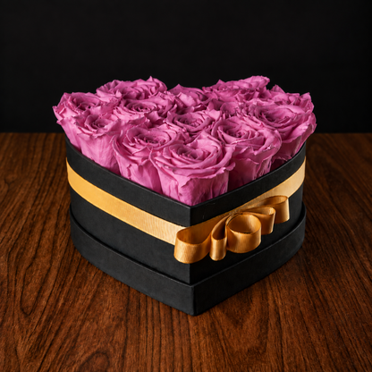 Caja de corazón con rosas preservadas en tono rosa intenso fucsia y listón dorado para cumpleaños