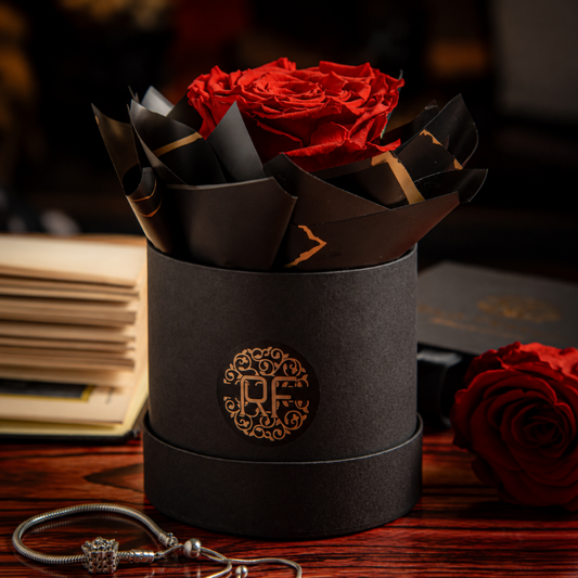 Rosa roja preservada que no se marchita montada en sombrerera negra con logo dorado para regalo