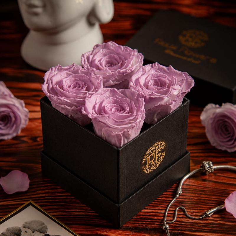 Caja de regalo negra con cuatro rosas preservadas en color morado lila para aniversario